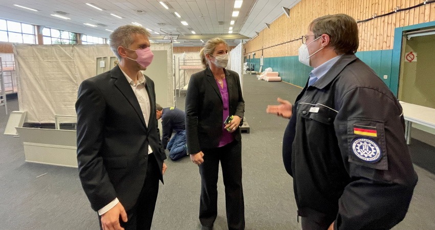 Inko Perkun, Ortsbeauftragter des THW-Ortsverbandes Lüneburg (r.) führt Lüneburgs Oberbürgermeisterin Claudia Kalisch und Lüneburgs neuen Sozialdezernenten Florian Forster durch die im Aufbau befindliche Notunterkunft in den Schlieffen-Hallen. Foto: Hansestadt Lüneburg.