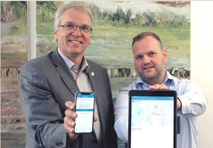 Landrat Jens Böther und Sascha Westermann, Fachgebietsleiter Brand- und Katastrophenschutz, zeigen die Warn-App BIWAPP. Foto: Landkreis Lüneburg (Archiv).