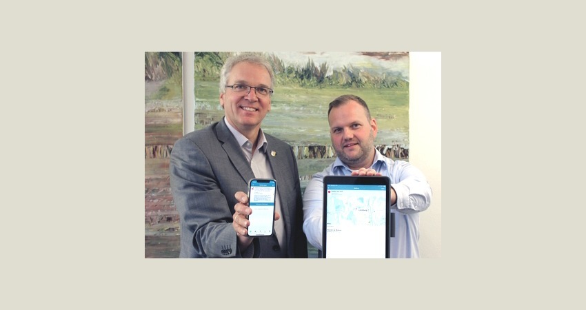 Landrat Jens Böther und Sascha Westermann, Fachgebietsleiter Brand- und Katastrophenschutz, zeigen die Warn-App BIWAPP. Foto: Landkreis Lüneburg, Juli 2023 (Archiv).