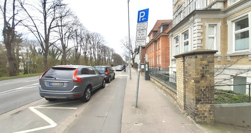 Foto: Lüne-Blog. Schießgrabenstraße in Lüneburg. Auf der wichtigen Nord-Süd-Verbindung, doch der Radweg und der Fußweg entsprechen nicht den gesetzlichen Vorgaben. Zudem sind sie zugestellt mit Schildern, Laternenmasten und mehr. Außerdem: Radfahrende sind durch "Dooring" gefährdet. Und ein Radweg auf der Gegenseite fehlt.