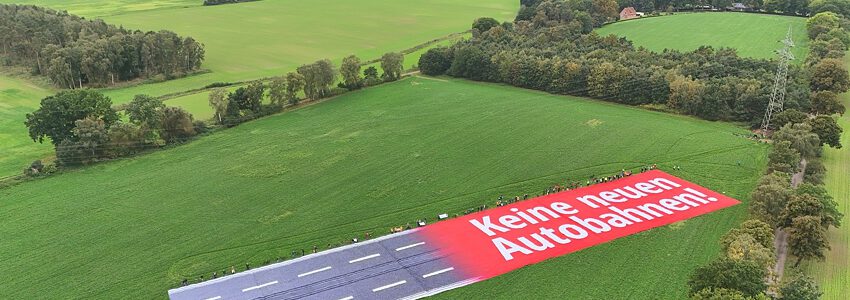 Banneraktion gegen die A39 am 01.10.2023: Das riesige Banner am Ort der geplanten Autobahn - tatsächlich noch viel breiter zerstört der Bau die Landschaft. Foto: Malte Hübner.
