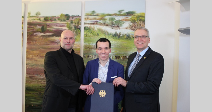 Foto: Landkreis Lüneburg. Von links: Kreisrat Rainer Müller und MOIN-Geschäftsführer Nikolas Wenzel überreichen Landrat Jens Böther den Förderbescheid aus Berlin.