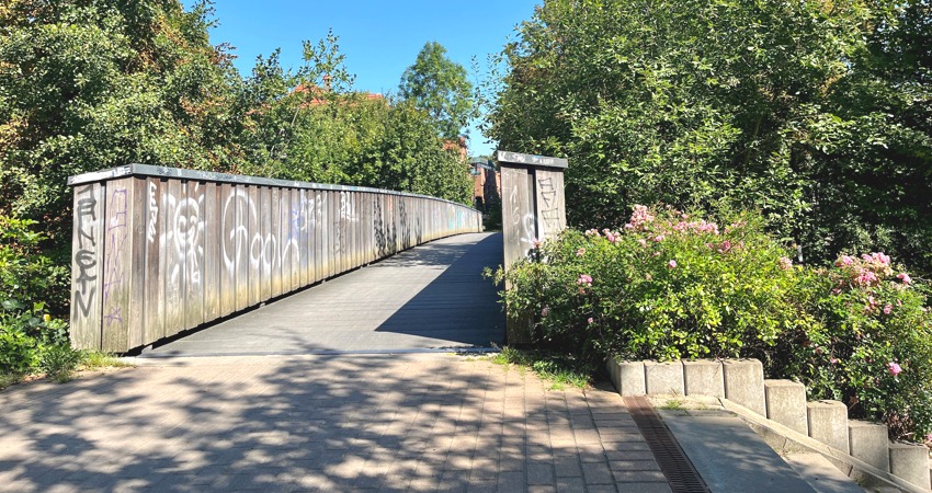 Foto: Hansestadt Lüneburg. Die Fußgängerbrücke zwischen Clamartpark und Wandrahmstraße ist wegen Scähden der an den Bohlen vorläufig für den Radverkehr gesperrt.  