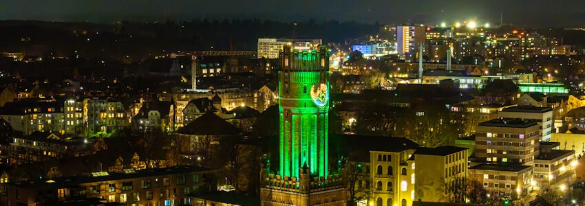 Foto: Lünedrohne. Beleuchteter Wasserturm in Lüneburg mit dem Logo von Fridays for Future.