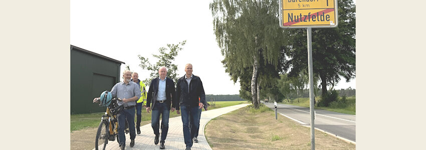 Foto: Landkreis Lüneburg. Schritten gemeinsam den neuen Radweg entlang der K28 ab (v.r.n.l.): Landrat Jens Böther, Laars Gerstenborn (Samtgemeindebürgermeister der Samtgemeinde Scharnebeck), Raino Fraedrich (Betrieb Straßenbau und -unterhaltung) und Tobias Winkelmann (Fachdienst Mobilität beim Landkreis Lüneburg). Foto: Andreas Tamme.