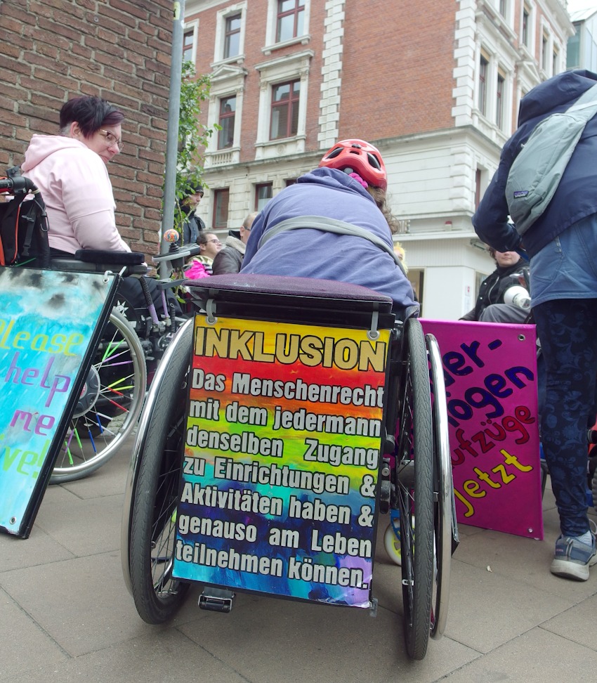 Foto: AAA LG. Forderung nach Inklusion. Teilnehmende im Rolli beim Protestzug der Antiableistischen Aktion Lüneburg am 4. Mai 2025 auf dem "Markt der Inklusion". Links im Bild: Daniela Laudan, Vorsitzende des Behindertenbeirats in Lüneburg.