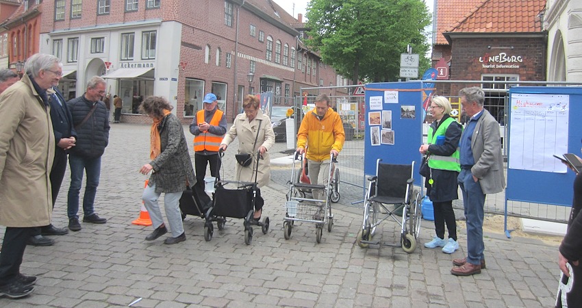 Foto: J. Korn. "Drei, zwo, eins ..." - gleich geht es los! Von links: Gerd Borchers (FUSS e.V.), Wolfgang Goralczyk (verdeckt), Reiner Netwall (ALA e.V.) Am Start machen sich schon mal bereit Karin Fischer, Christel John und Markus Moßmann. Daneben Julia Born und Dr. Michael Perschmann , Ratsmitglied für Bündnis 90/Die Grünen. Manbeachte die Gefäße mit Wasser, die jeweils an der Gehhilfe angebracht sind. Es gilt, schnell zu sein, aber möglichst wenig zu verschütten!