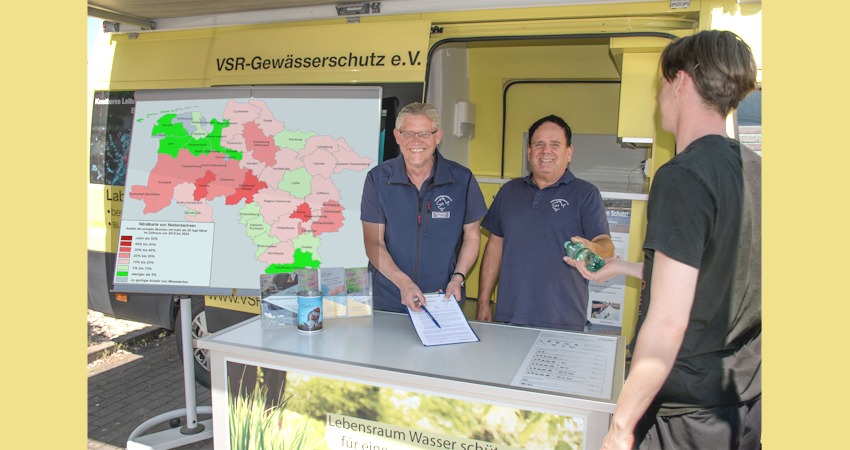 Matthias Ahlbrecht und Frank Sombrowski nehmen die Wasserprobe eines Brunnenbesitzers entgegen. Links die Nitratkarte vom Landkreis Lüneburg. Foto: Harald Guelzow.
