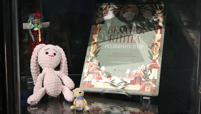 Foto: Museum Lüneburg. Exponate in der ersten Ausstellungsvitrine im Dezember 2024: Ein Kuscheltier, das ein Kind während der Flucht tröstete, ein Kinderbuch mit Spielen und eine traditionelle Motanka-Puppe. Die Objekte erzählten von der Ungewissheit der Flucht, der Sehnsucht nach Heimat und dem Neubeginn in der Fremde. 