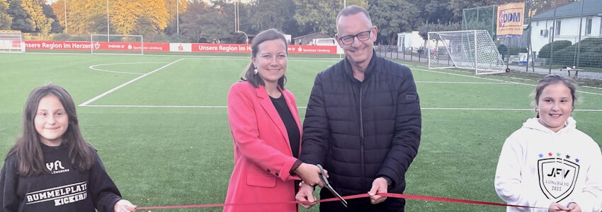 Foto: Hansestadt Lüneburg. Bürgermeisterin Jule Grunau und Lüneburgs Sportdezernent Matthias Rink durchschnitten das rote Band und eröffneten damit den neuen Kunstrasenplatz, den die Hansestadt mit 500.000 Euro unterstützt hat.