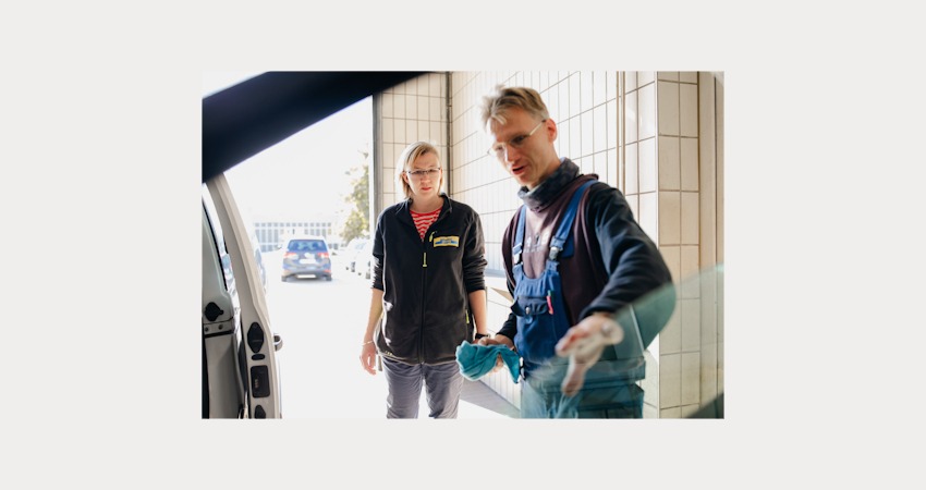 Lebenshilfe Lüneburg-Harburg gGmbH. Schichtwechsel 2025. Lebenshilfe-Mitarbeiter Michael zeigt Isabell Küster vom Reifendienst Lodders die richtige Autoinnenpflege.