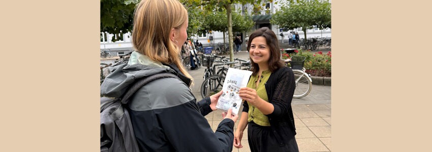 Foto: Hansestadt Lüneburg. Merve Künkenrenken aus dem Bereich Mobilität verteilt im Rahmen der anstehenden Mobilitätswoche Infomaterial insbesondere an Pendler:innen in Lüneburg.