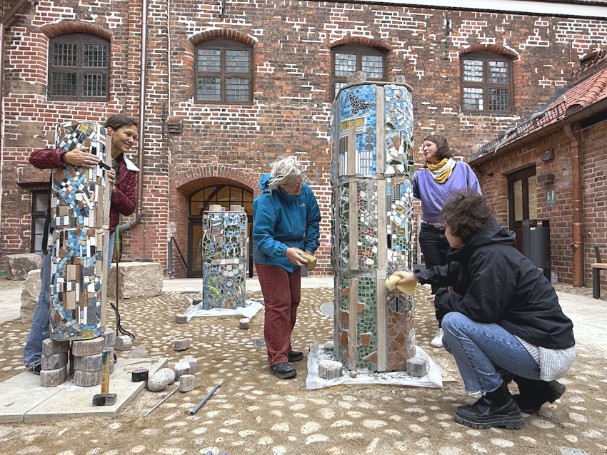Foto: Hansestadt Lüneburg. Bevor der Hof bepflanzt wird, sind dort Skulpturen der Ikarus-Kunstschule zu bewundern, entstanden in Workshops. Die Mosaik- und Keramikskulpturen werden in diesen Tagen aufgestellt von Djamila Zeranski (links, Projektleiterin bei der Hansestadt), Margaretha Stumpenhusen und Julia Schulte (Vorstand) und Maike Stumpenhusen (Leitung der Kunstschule).