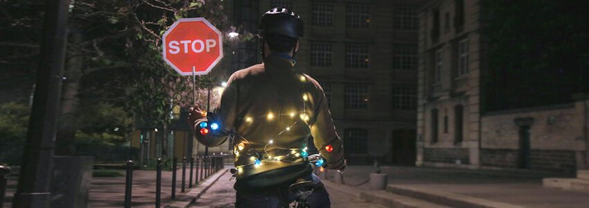 Radfahrer auf dunkler Straße - mit bunten Lichtern und eigenem Stoppschild. Foto: Velotaf, Pixabay.