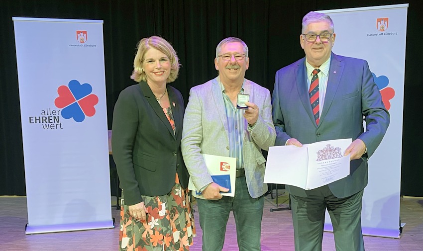 Foto: Hansestadt Lüneburg. Die Ehrenmedaille der Hansestadt Lüneburg ging 2025 an Michael Gimball (Mitte) für sein Engagement im Ochtmisser SV. Laudator und Ochtmissens Ortsbürgermeister Jens-Peter Schultz und Lüneburgs Oberbürgermeisterin Claudia Kalisch gratulierten. 