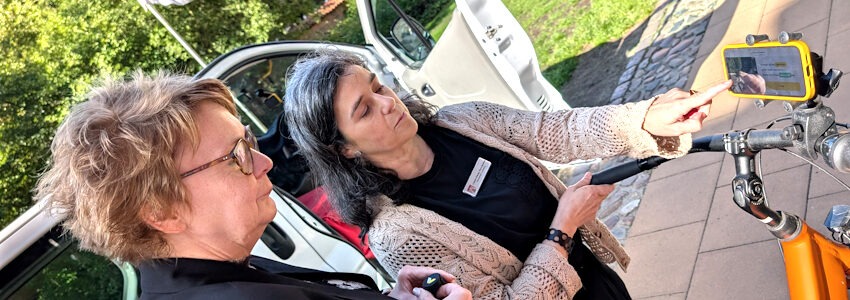 Foto: Hansestadt Lüneburg. Laura Pérez Fernández (rechts) erklärt Ministerin Daniela Behrens, wie die Stadtverwaltung per Auto und Fahrrad mit KI-Unterstützung den Zustand der Lüneburger Straßen erfasst.