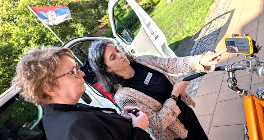 Foto: Hansestadt Lüneburg. Laura Pérez Fernández (rechts) erklärt Ministerin Daniela Behrens, wie die Stadtverwaltung per Auto und Fahrrad mit KI-Unterstützung den Zustand der Lüneburger Straßen erfasst.
