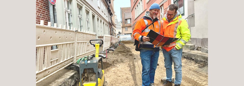 Foto: Hansestadt Lüneburg. Björn-Olde Backhaus (links) und Stefan Hammer aus dem Bereich Straßen- und Brückenbau bei einer Baustellenbesprechung in der Rotehahnstraße, 12/2025.