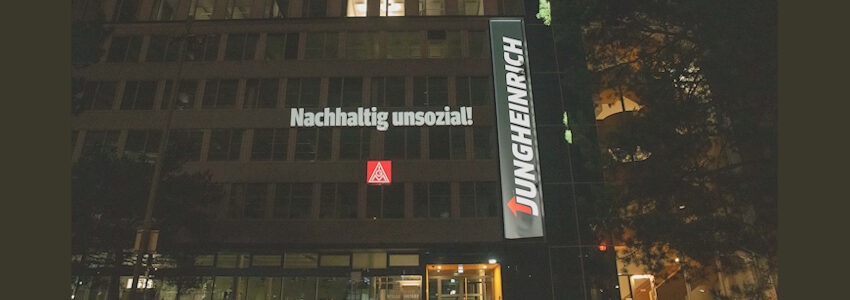 Foto: IG Metall Hamburg, Heiko Stumpe: Lichtprojektion an der Konzernzentrale von Jungheinrich in Hamburg-Wandsbek: „Jungheinrich – nachhaltig unsozial“.