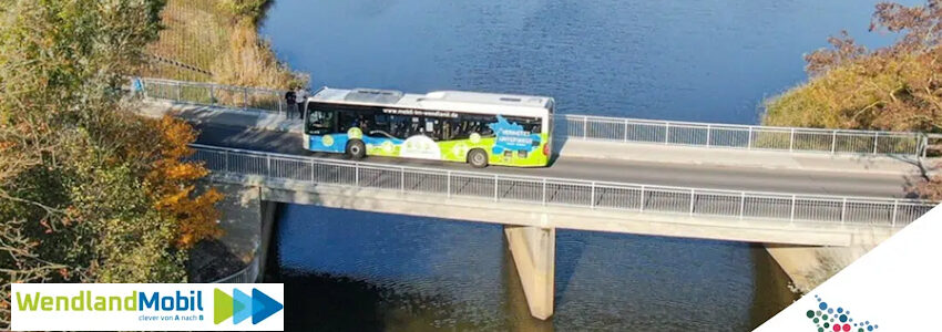 Foto: WendlandMobil / Landkreis Lüchow-Dannenberg, Sharepic (angepasst). Bus von WendlandMobil fährt über eine Brücke.
