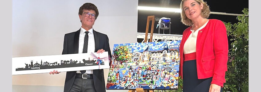 Foto: Hansestadt Lüneburg. Zum 50. Jahrestag der Städtepartnerschaft brachte OB Claudia Kalisch ihrem französischen Kollegen Yves Coscas die aus Metall gesägten, verbundenen Skylines der Städte Lüneburg und Clamart mit. Im Gegenzug bekam sie ein Gemälde vom Mairie de Clamart, dem Rathaus der Stadt, geschenkt.