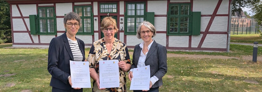 Fotos: Hansestadt Lüneburg. Dr. Carola Rudnick (Mitte, Leiterin der „Euthanasie“-Gedenkstätte) freut sich mit Erster Kreisrätin Yvonne Hobro (links) und Lüneburgs Bildungsdezernentin Gabriele Scholz (rechts) über die unterschriebene Zuschussvereinbarung.