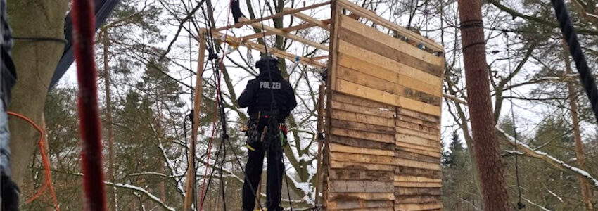 Foto: KlimaKollektiv. Polizist im halb demontierten Baumhaus im Lüner Holz am 12.01.2026.