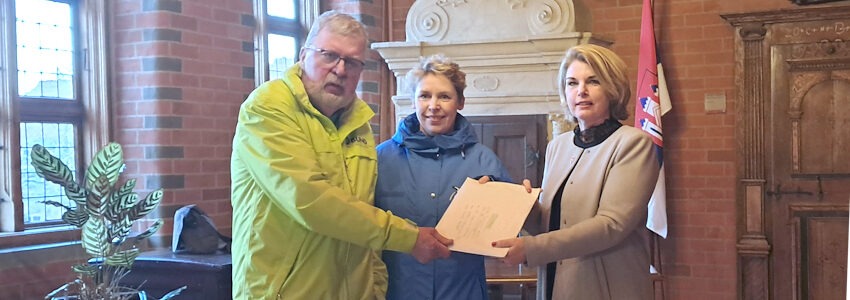 Foto: BUND, NABU Lüneburg. Lüneburg. 16. März 2026: Bernhardt Stilke (BUND) und Anette Reinhardt (NABU) übergeben die Petition zum Stopp des Feuerwerks an den Sülzwiesen an OB Claudia Kalisch.