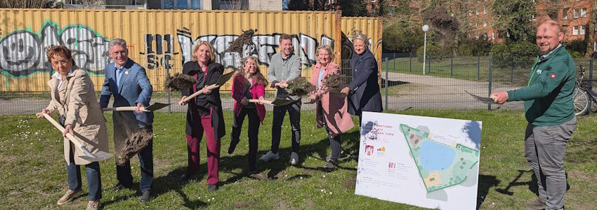 Foto: Hansestadt Lüneburg. Beim Spatenstich am 9. April 2026 - von links: Christel John, Frank Soldan, Claudia Kalisch, Landschaftsarchitektin Pamela Münch, Pascal Mennen, Quartiersmanagerin Andrea Szymanski, Vivien Hoffmann und Bauleiter Micha Jirjahn.