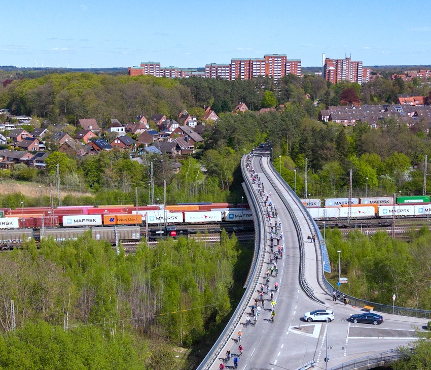 Foto: Lünedrohne. Demonstration gegen die A39 auf der Ostumgehung Lüneburg am 26. April 2026 - mit den Hochhäusern von Kaltenmoor im Hintergrund. Luftbild.
