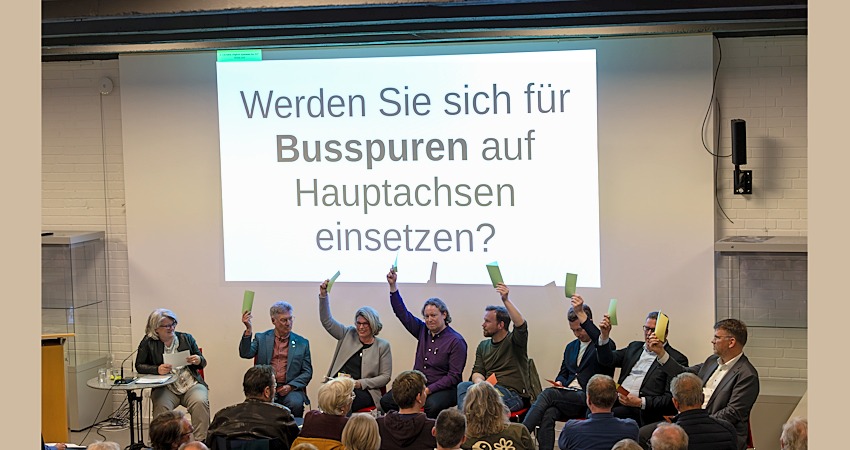 Foto: Malte Hübner. Schnellabstimmung beim Podium mit den OB-Kandidierenden am 16. April 2026: Werden Sie sich für Busspuren auf den Hauptachsen einsetzen? Alle stimmen zu - nur Oliver Wozniok (SDD) enthält sich.