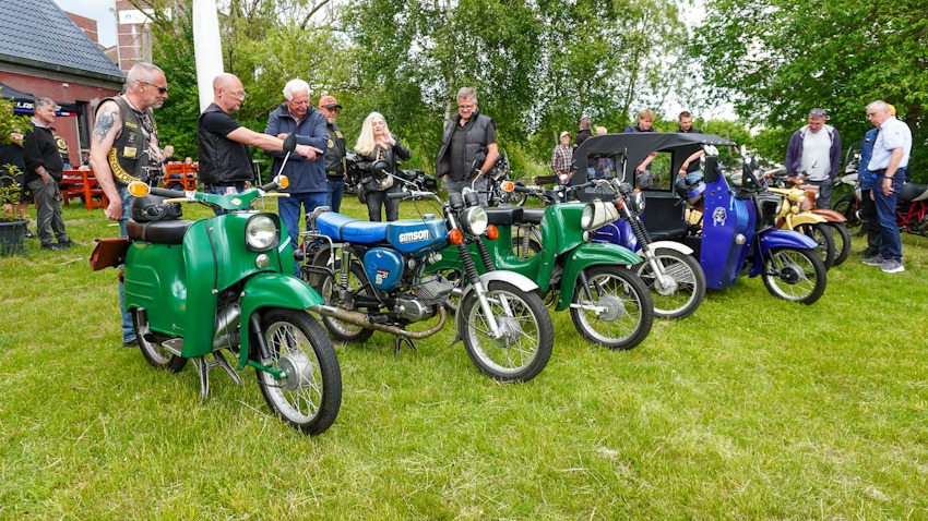 Foto: Ralph Rüdiger Cornels. Embsen, 30. Mai 2026. Auf der Wiese hinter dem Clubhaus des Motorradclubs „Dark Knights MC Lüneburg" haben die Simson-Enthusiasten ihre Schätze aufgestellt: Mehrere S51, eine Schwalbe und weitere Modelle aus Suhl locken Mitglieder und Gäste der Dark Knights aus der Reserve. Man bückt sich, zeigt, erklärt und staunt – so sieht Leidenschaft aus, egal ob für 50 ccm oder 1800.