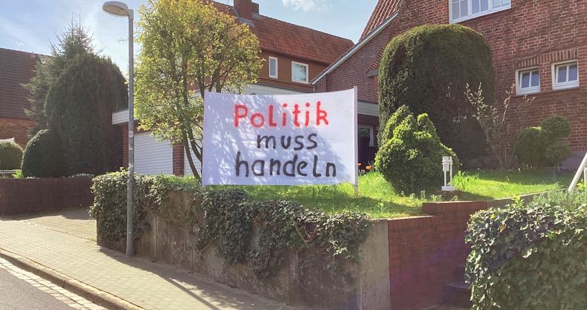 Foto: Initiative Erbbau Lüneburg. Rund 3500 Grundstücke in Lüneburg gehören nicht den Eigentümer*innen der Häuser, die darauf stehen, sondern sind sogenannte Erbpachtgrundstücke. Der Pachtzins orientiert sich am Bodenwert - und der ist in den letzten Jahren sprunghaft gestiegen. Doch bis zu 1.000 Euro monatlich an Erbbauzinsen – das können sich viele Hauseigentümer nicht zusätzlich leisten. Deshalb hier das Transparent an einem der Häuser: "Politik muss handeln".