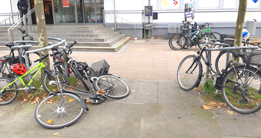 Foto: FUSS e.V. Lüneburg. Bahnhofsvorplatz. Auf dem Boden liegende Fahrräder sind für Menschen mit Sehbehinderung eine erhebliche Gefahrenquelle. Wer mit Rollator oder Rollstuhl unterwegs ist, braucht ausreichende Wegebreiten.
