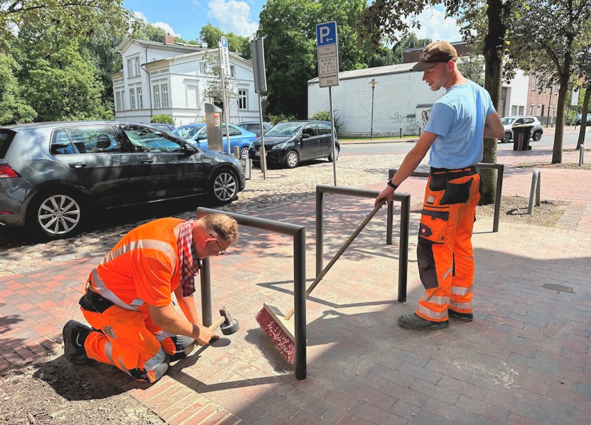 Foto: Hansestadt Uelzen. Zwei Mitarbeiter der Betrieblichen Dienste Uelzen montieren neue Fahrradbügel.
