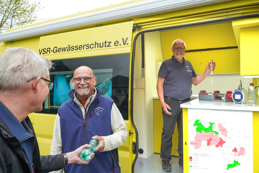 Foto: Ruben Wiltsch. Frank Hage im Gespräch mit einem Brunnenbesitzer. Harald Gülzow im Labormobil untersucht eine Brunnenwasserprobe.