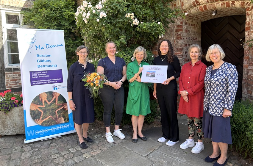 Foto:  Kloster Lüne. Von links: Äbtissin Gräfin zu Dohna, Anneke Potten, stv. Leitung von MaDonna. Dritte von rechts: Linn Graves, Leitung von MaDonna. Um sie herum weitere Konventualinnen des Kloster Lüne.
