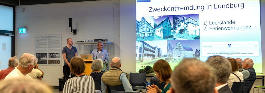 Foto: Malte Hübner. Am 21. August 2026 hatte die Initiative WohnWende Vertreter*innen der örtlichen Parteien eingeladen zum Thema Wohnraummangel in Lüneburg. Zu Beginn informierten Jonas Korn (WohnWende) und Reiner Netwall (ALA) über Zweckentfremdung von Wohnraum in Lüneburg - durch Leerstände und Ferienwohnungen.