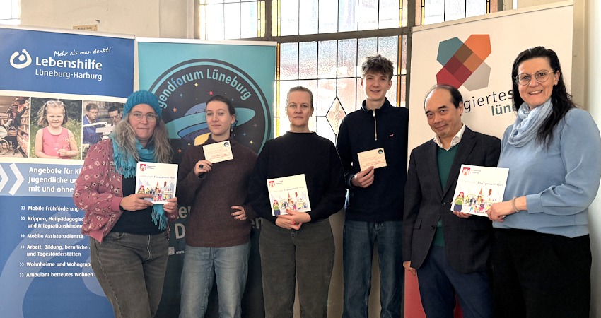 Foto: Hansestadt Lüneburg. Für die Wilhelm-Raabe-Schule nahm der stellvertretende Schulleiter André Choi (2. v. r.) die Broschüre zum Lüneburger Engagement-Plan in leichter Sprache entgegen. Mit ihm freuen sich (v. l.): Britta Habenicht (Ehrenamtskoordinatorin der Lebenshilfe Lüneburg Harburg), Sophie Westphal (Jugendforum Lüneburg), Christine Donner (Leitung der Freiwilligenagentur Lüneburg des Paritätischen Wohlfahrtsverbandes Lüneburg), Max Süling (Jugendforum Lüneburg) und Kathrin Wolter (Koordinierungsstelle Ehrenamt der Hansestadt Lüneburg).